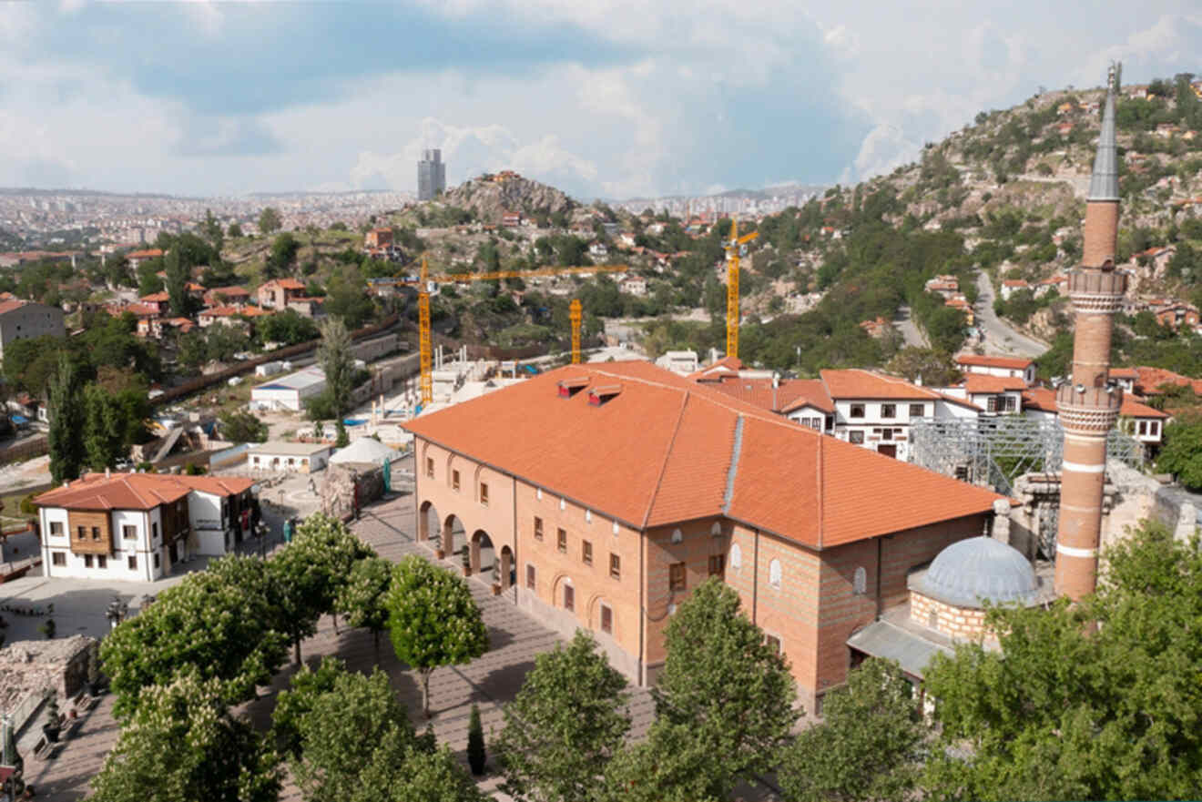 An aerial view of Hacı Bayram Mosque in Ankara, a historic place of worship with its distinctive minaret overlooking the cityscape, contrasting modern construction in the background