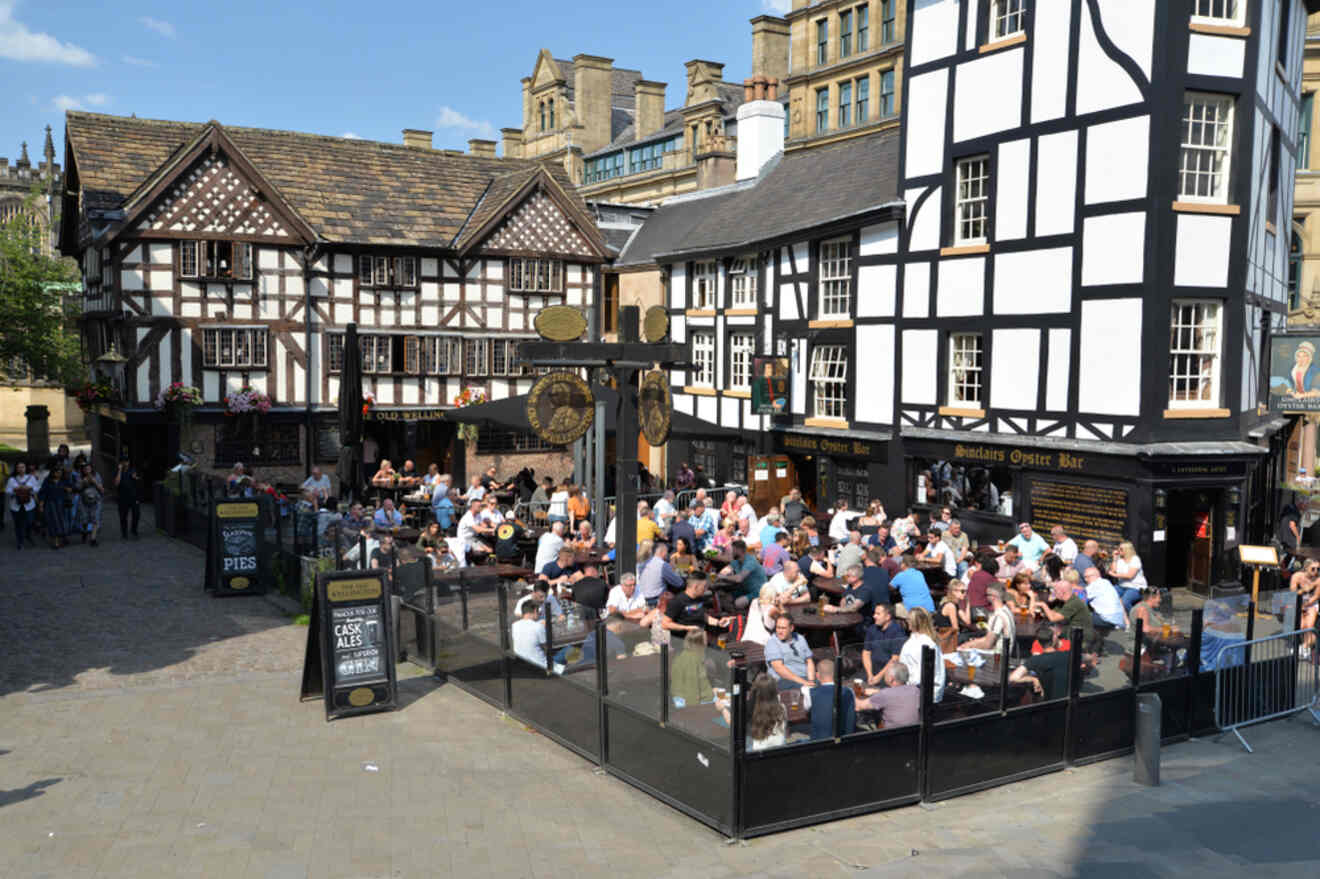 The bustling Old Wellington pub in Manchester with outdoor seating filled with patrons enjoying drinks in the sun