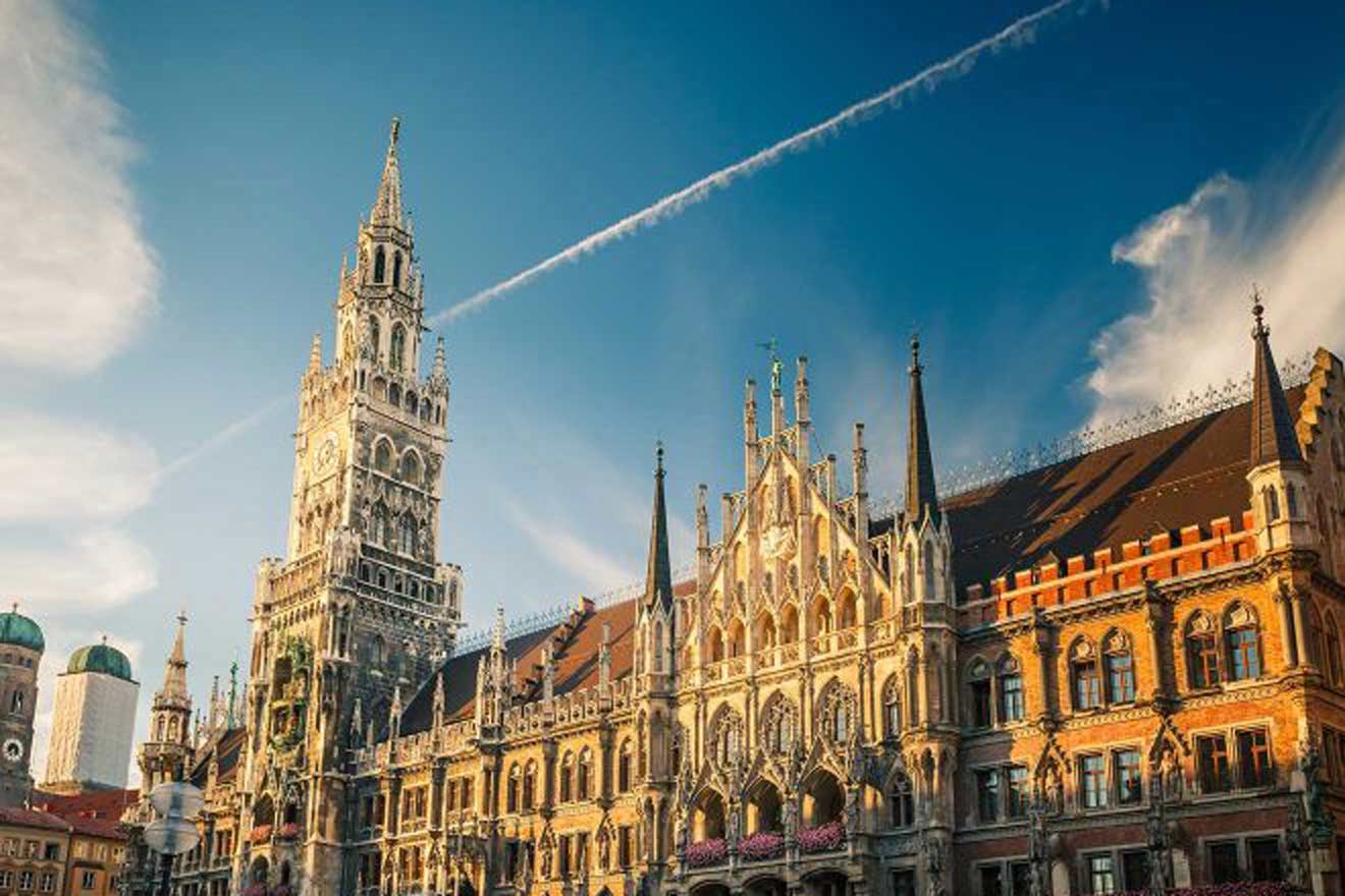 Munich's New Town Hall (Neues Rathaus) with its intricate Gothic Revival architecture and the towering spire of its clock tower, bathed in the warm light of a setting sun