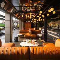 Modern outdoor lounge area at the Kimpton Hotel Monaco with round hanging lights and curved leather sofas