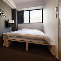 A modern minimalist bedroom in a Japanese hotel with a large bed