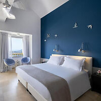 Elegant bedroom interior with a deep blue accent wall and white linens