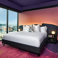 Luxurious bedroom with a large bed featuring white bedding and plush pillows, and a window with a cityscape view