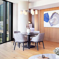 A modern dining room with a circular table and four textured grey chairs