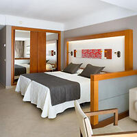 Hotel bedroom with a contemporary design, featuring a large bed with grey and white linens