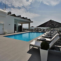 Sleek rooftop infinity pool surrounded by white sun loungers and black parasols