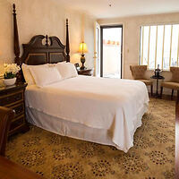 Elegant room at the Penn’s View Hotel featuring a classic four-poster bed and two armchairs