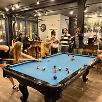 Lively game room at Apple Hostels with people enjoying a game of pool