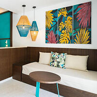 Resort lounge area with vibrant tropical wall art and a long, cushioned bench