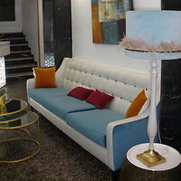 Stylish interior featuring a blue and white sofa with colorful cushions, accompanied by a white floor lamp