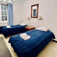 Traditional twin bedroom with royal blue bedspreads and light blue curtains