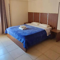 Minimalist hotel room with a large bed covered in a blue comforter and wooden headboard