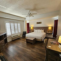 Budget hotel room with a large bed and wooden floors at Naples Park Central Hotel