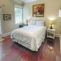 Cozy hotel room with queen bed, white linens, and hardwood floors
