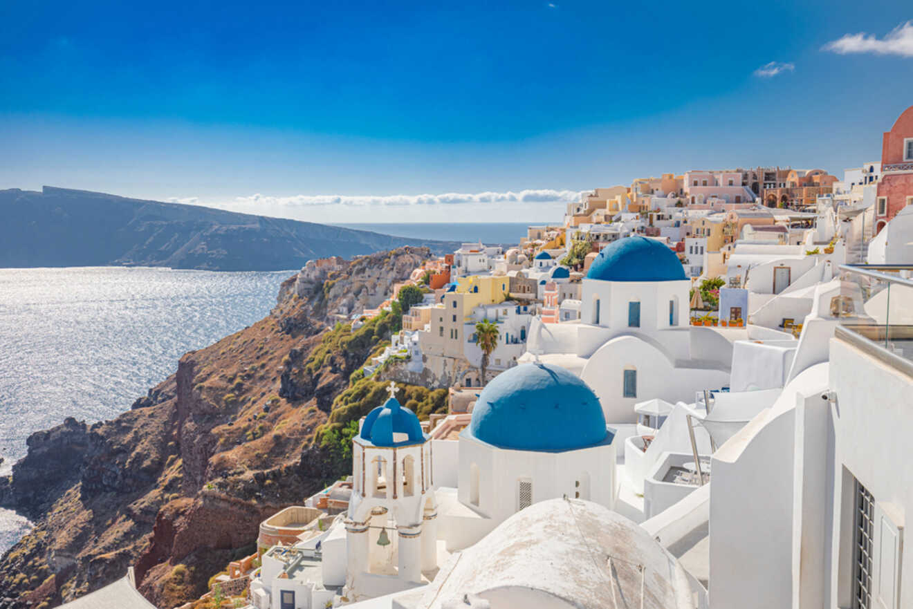 Sweeping view of Fira, the bustling capital of Santorini, showcasing the white buildings with blue domes perched on cliffs above the glistening Aegean Sea