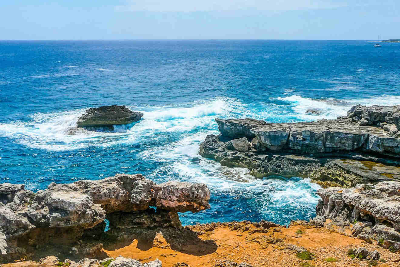 Rugged coastal landscape in Southeast Menorca featuring dynamic blue waves crashing against a sharp limestone cliff, embodying the raw beauty of the Balearic Islands