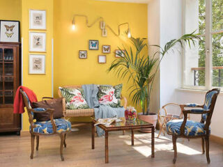 An inviting corner in a boutique hotel with a sunny yellow wall and eclectic art frames