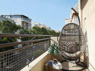Cozy balcony with a wicker egg chair and urban view