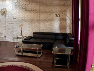 Elegant sitting area featuring a black leather couch, vintage side tables, and exposed brick walls