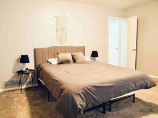 A simple yet elegant bedroom featuring a large bed with a gray upholstered headboard