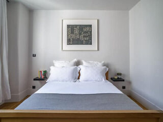 A minimalist bedroom with a large bed dressed in white linens