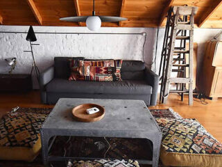 Cozy loft-style living room with a grey sofa, eclectic rugs, a large central concrete coffee table