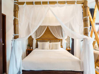 Romantic bamboo canopy bed with white draping in a rustic Krabi villa