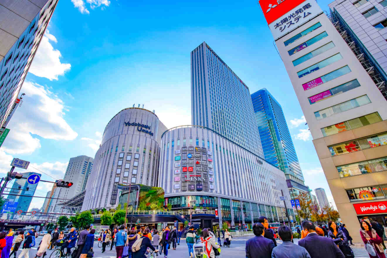 Vibrant urban scene showing pedestrians crossing a street surrounded by modern buildings under a clear blue sky.