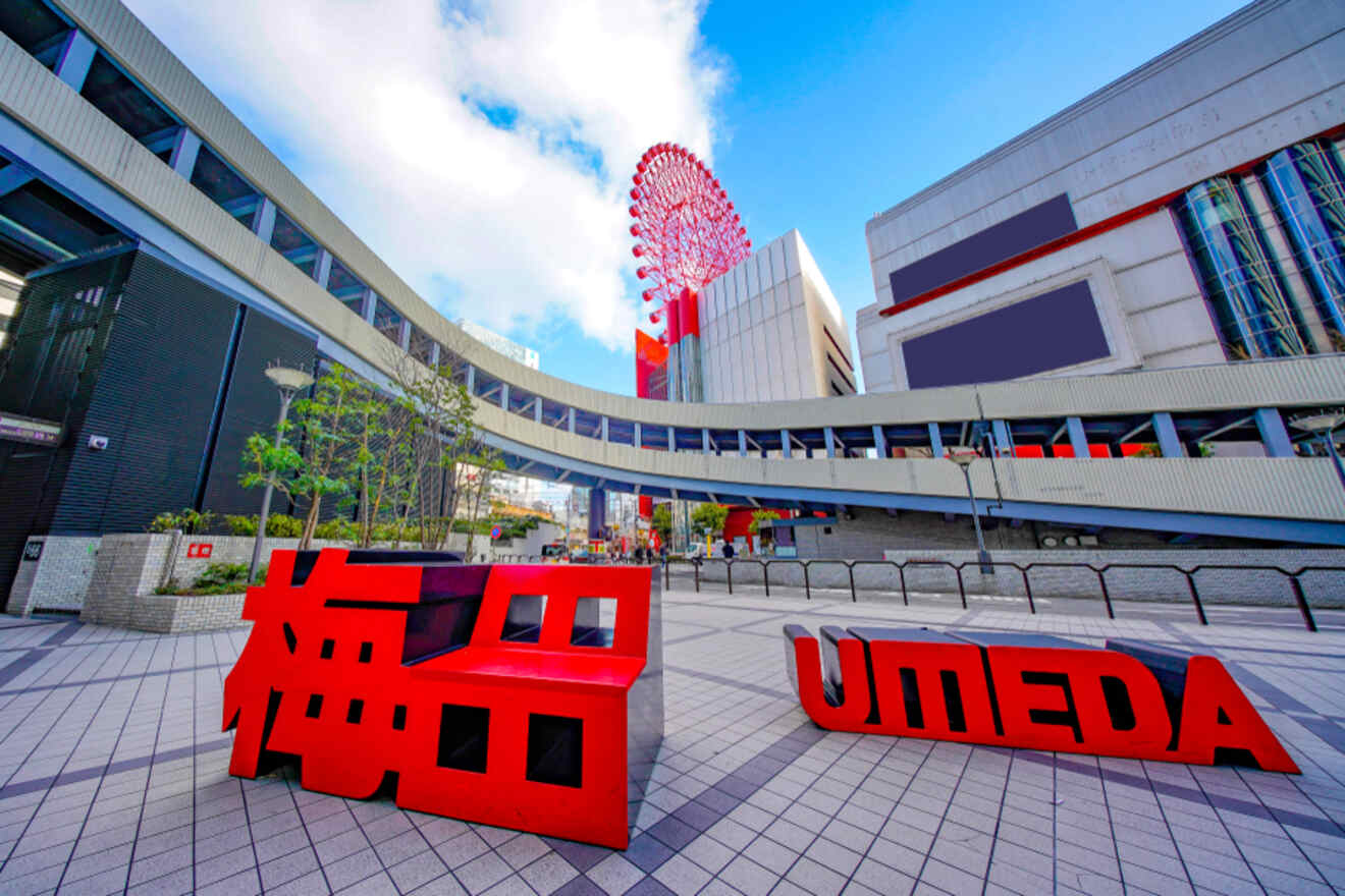 View of umeda district with a large red ferris wheel atop a building, modern architecture, and a bold red "umeda" sign in the foreground.