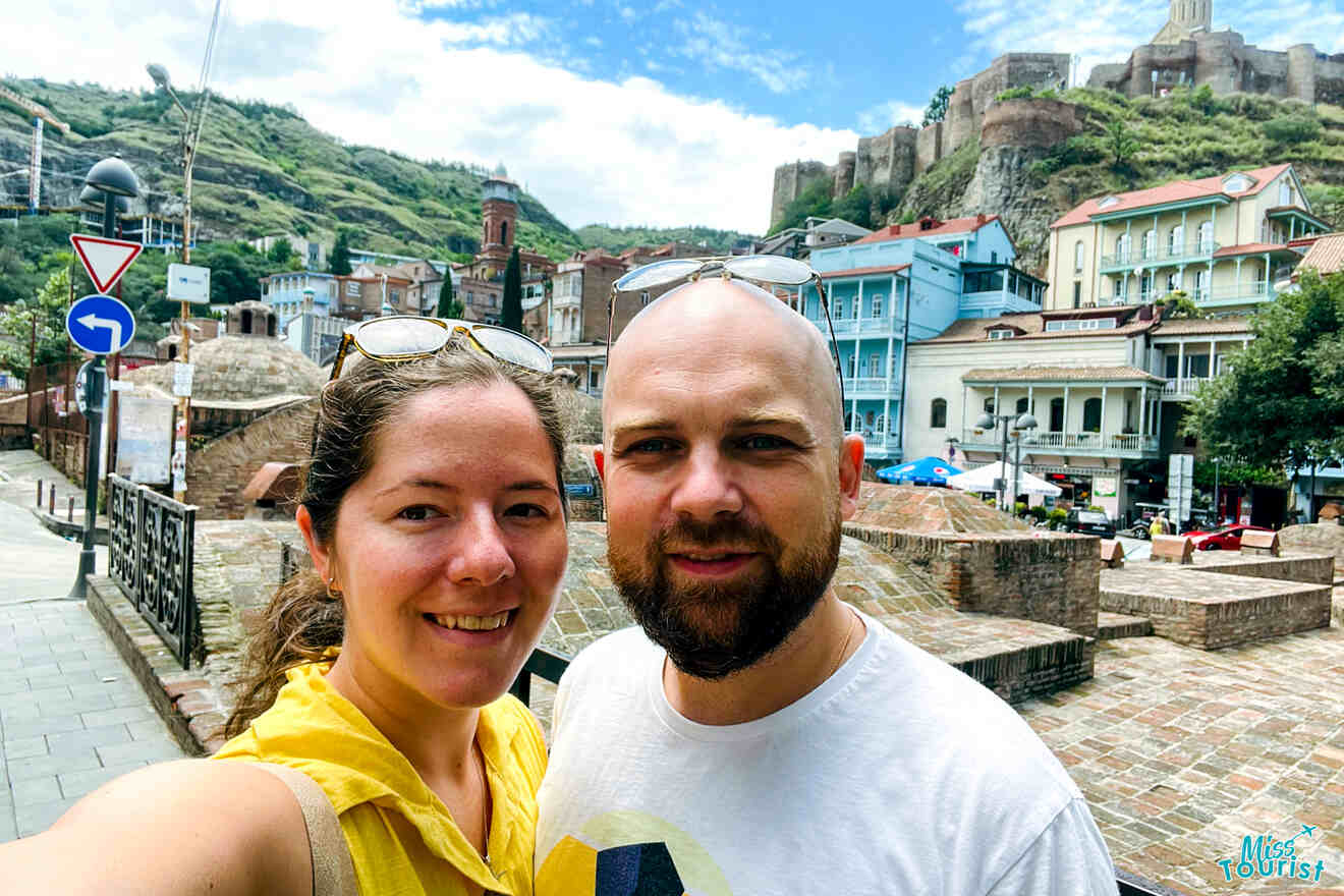 The writer of the post and her partner posing for a selfie with the Narikala Fortress in the background, reflecting a personal moment set against Tbilisi's rich historical backdrop