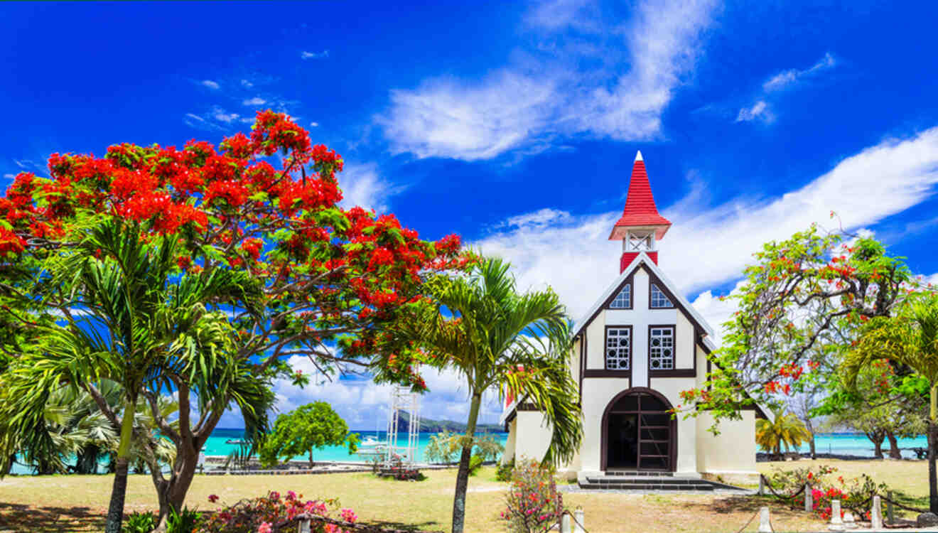 Charming church with a red roof nestled among vibrant tropical flora, with a clear blue sky above in Mauritius