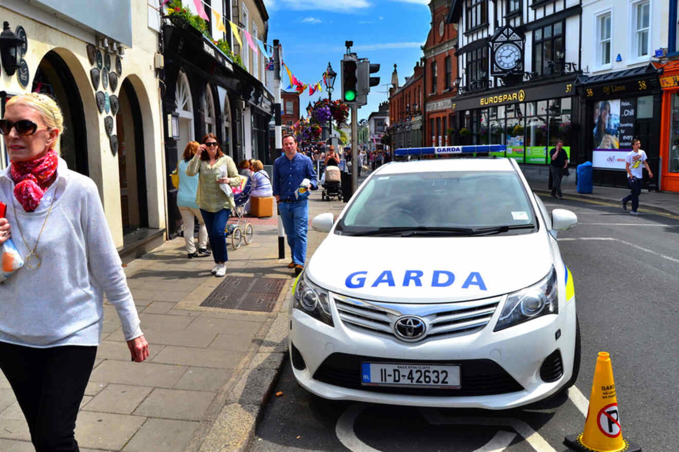 Garda patrol car parked on a busy street with pedestrians