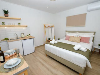 Studio apartment with an integrated kitchenette and a plush bed with decorative pillows