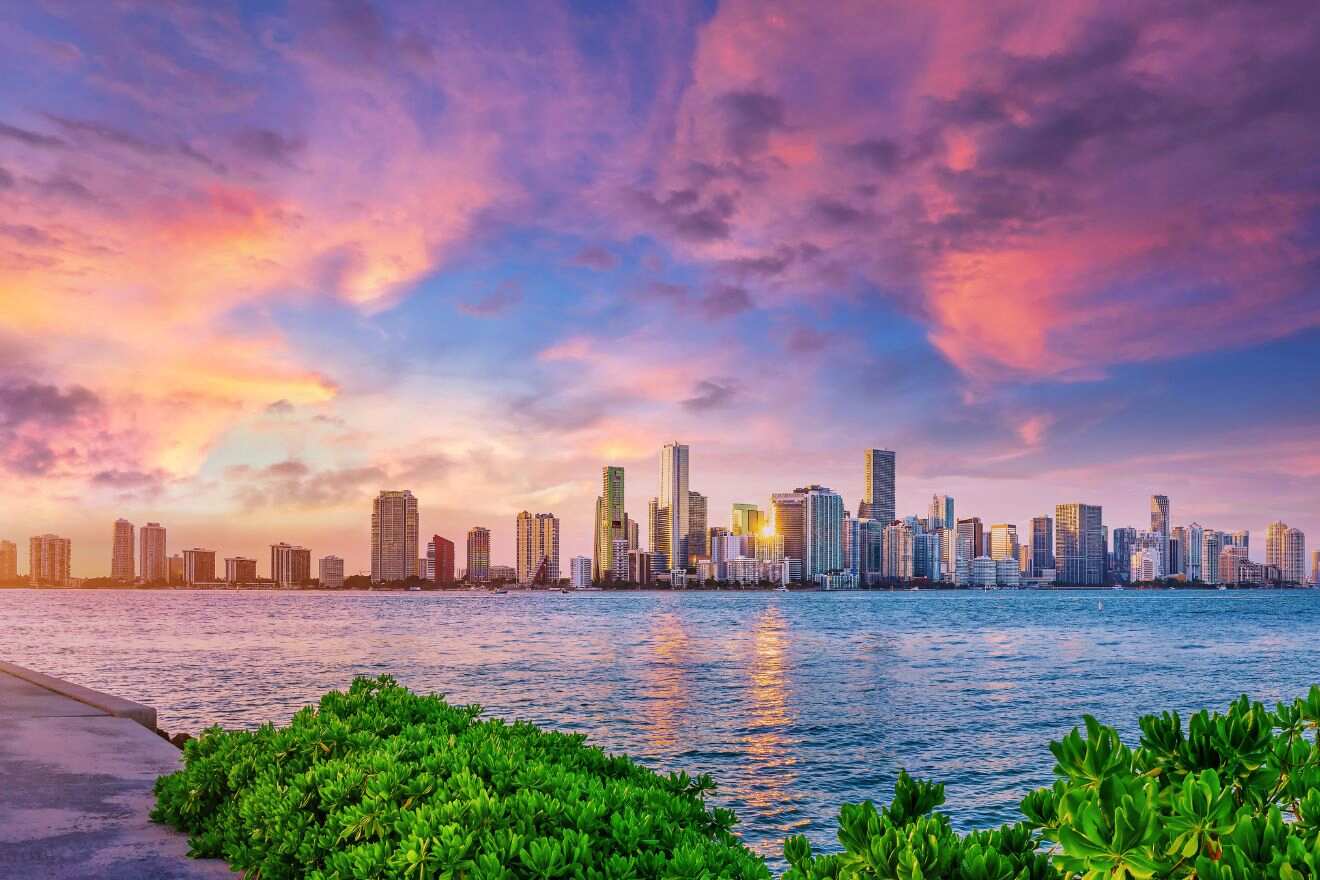 Skyline of Miami at sunset with pink and blue hues reflecting off the high-rises and calm waters