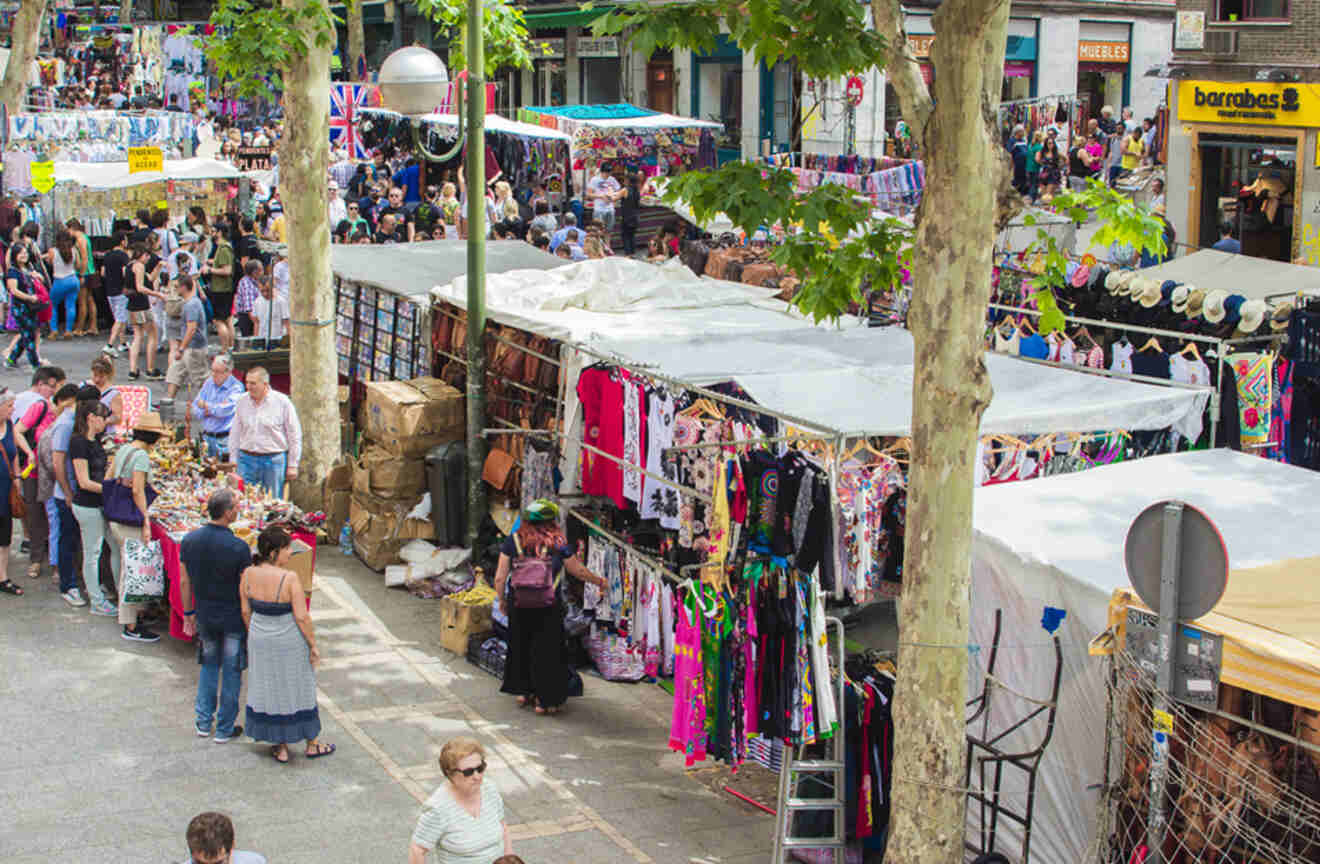 Crowded scene at El Rastro, Madrid's popular outdoor flea market, with rows of stalls under the shade of trees