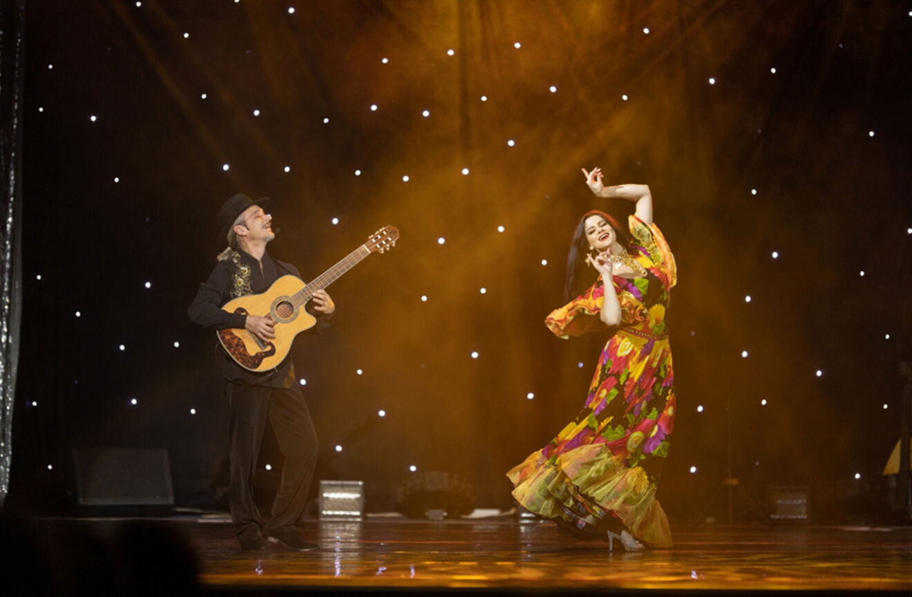 Dynamic flamenco performance in Madrid with a female dancer in a colorful dress and a male guitarist on stage under spotlight