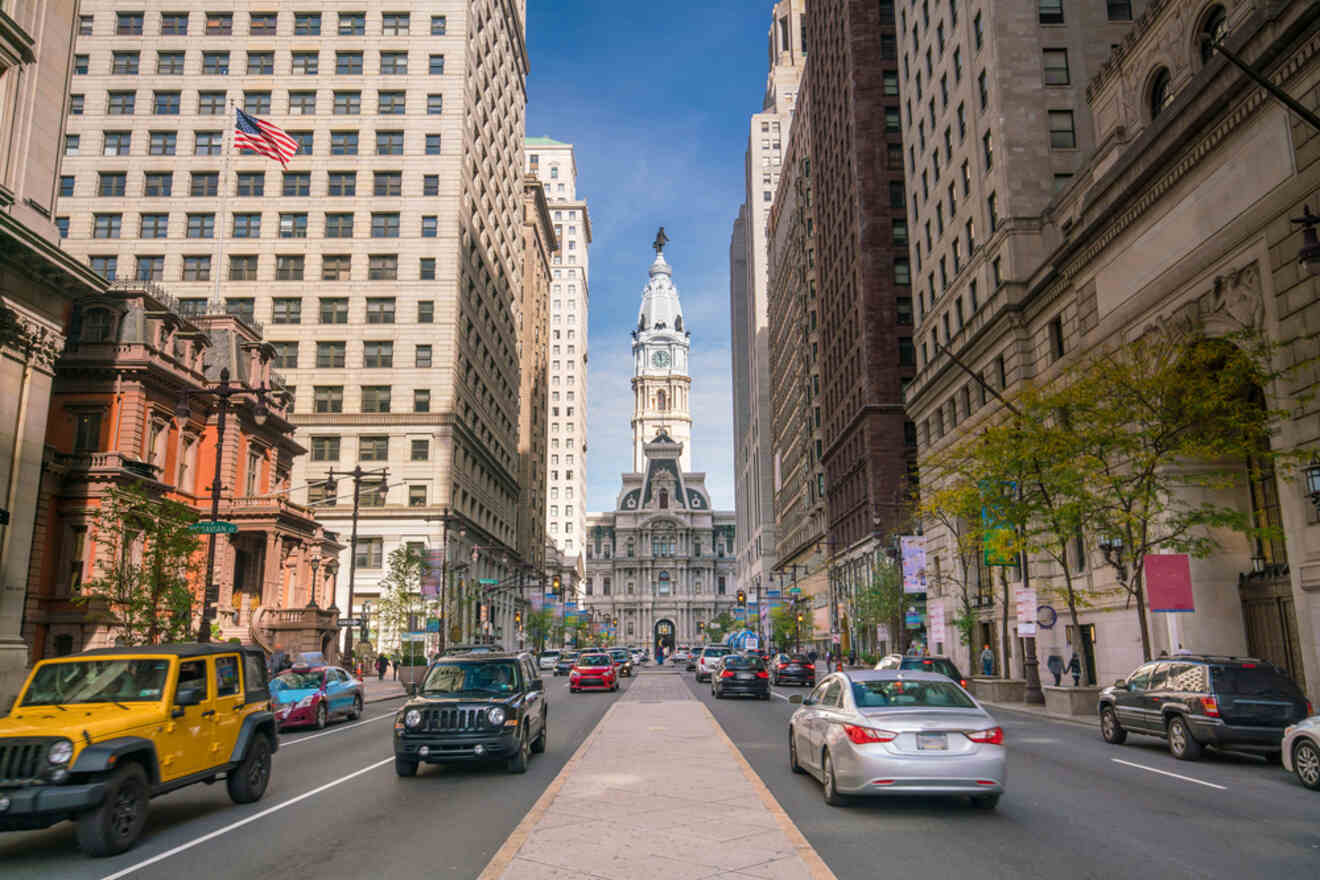 Busy urban street view of Center City, Philadelphia, with cars and pedestrians, leading towards the historic City Hall with its prominent clock tower