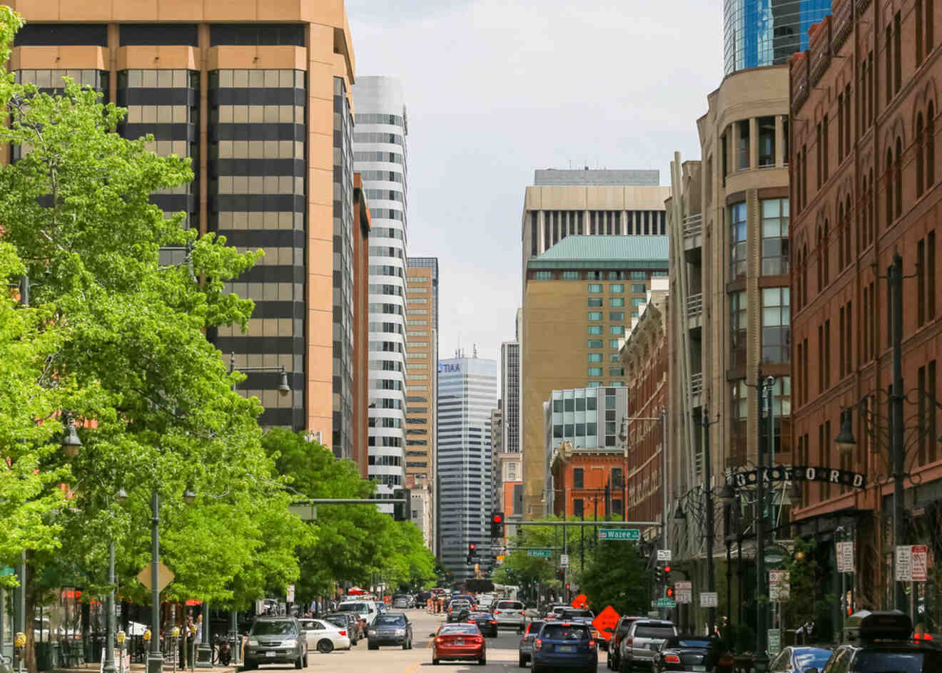 Vibrant street view in Downtown Denver, lined with green trees and a mixture of modern and traditional buildings