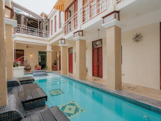 A serene indoor pool surrounded by a colonial-style building with relaxing poolside loungers.
