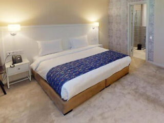 A cozy modern bedroom featuring a plush bed with a blue ornate pattern comforter
