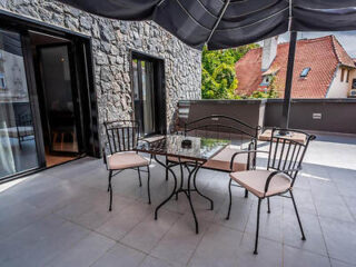 Spacious balcony area with metal chairs and table, ideal for outdoor dining, partially shaded by an umbrella