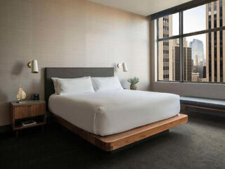 Contemporary bedroom with a large bed centered between two windows, with a view of the city skyline