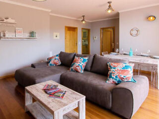 A welcoming living room with a large, plush grey sofa adorned with vibrant coral pillows and a rustic coffee table