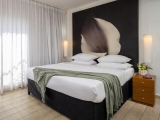 Modern hotel bedroom with artistic feather mural above the bed