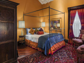 Luxuriously decorated bedroom with a four-poster bed, intricate oriental rugs, and antique furniture