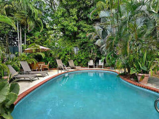 Tranquil poolside setting with sun loungers and dense tropical foliage