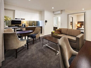 Elegant and spacious living area in a deluxe one-bedroom apartment with plush seating, a dining area, and a kitchen