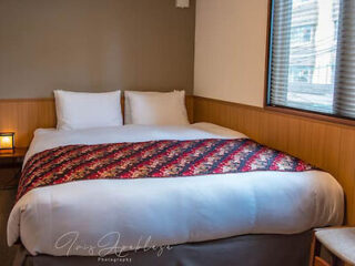 A comfortable hotel room with a large bed covered in a vibrant red and black patterned quilt