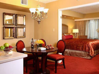 Elegant suite dining area with a chandelier, round table, and plush red seating