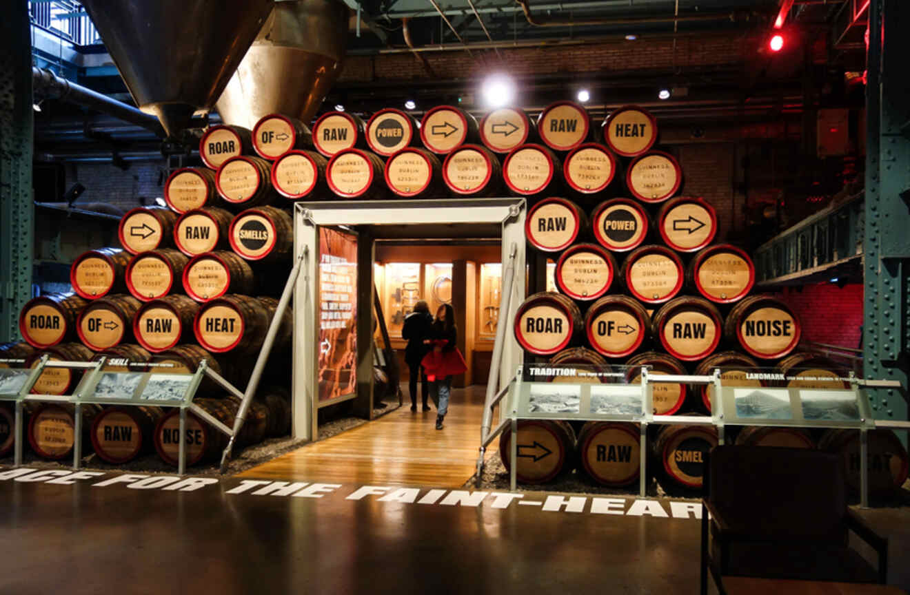 Entrance to the Guinness Storehouse in Dublin, with whiskey barrels labeled with words like 'ROAR' and 'HEAT,' conveying the brewing process atmosphere.